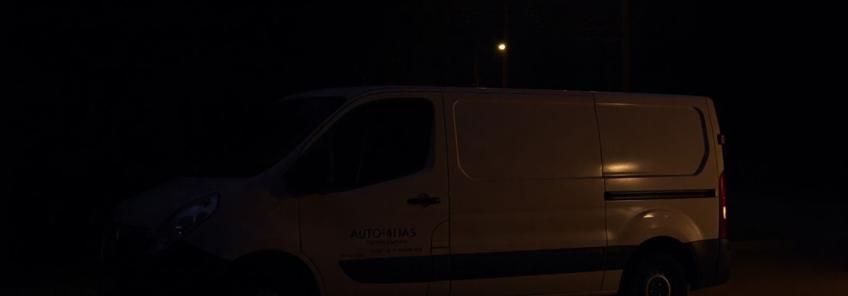 Tradesperson's van in dark, shadowy street at dusk.