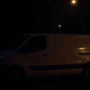 Tradesperson's van in dark, shadowy street at dusk.