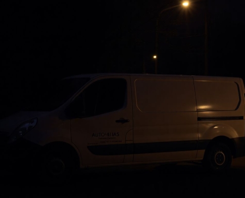 Tradesperson's van in dark, shadowy street at dusk.